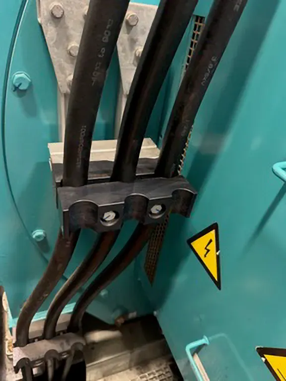 Close-up of îd-Technik cable clamps holding multiple MV power cables in place within a high-voltage electrical enclosure.