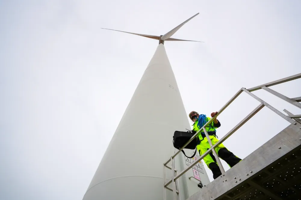 Electrical technician inspecting a wind turbine tower, representing the medium-voltage environments where cable clamps and HRC fuse links are used.